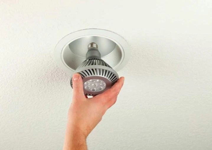 Ruka vyndává LED lampu ze stropního svítidla.