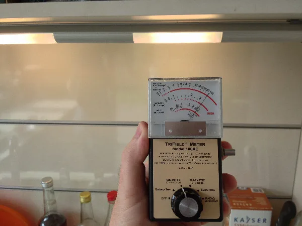 Ruční přístroj měřící elektromagnetické pole u indukční varné desky.