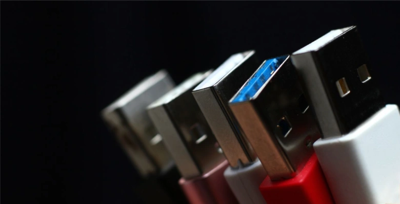 USB konektory různých barev a typů na černém pozadí.