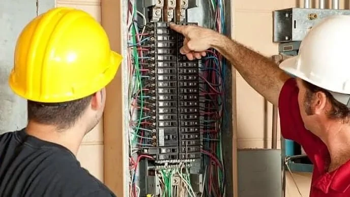 Elektrikáři kontrolují jistič v rozvodnici.