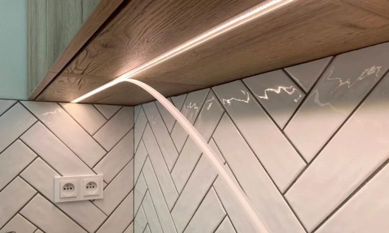 LED pásek pod skříní s viditelným napájecím kabelem.