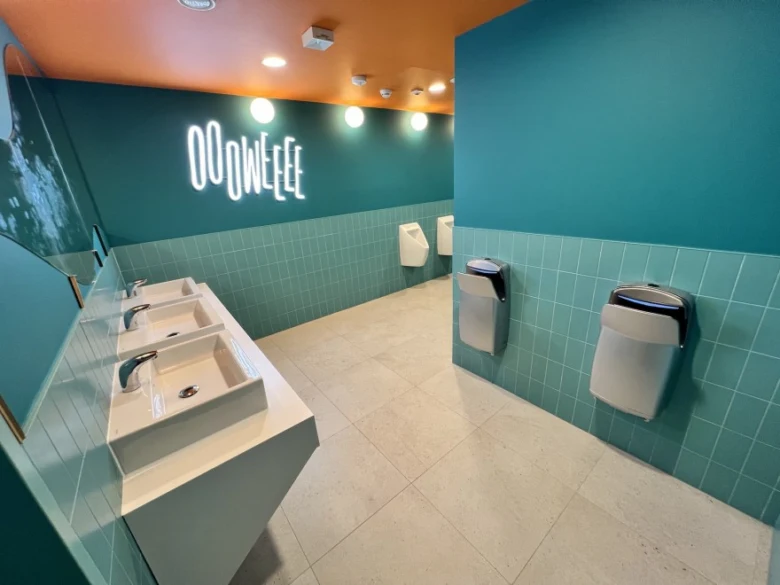 Moderní toalet s pisoáry na zdi a umyvadly v interiéru.