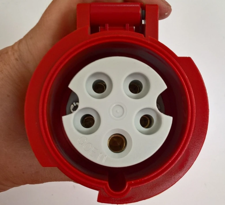 Červený průmyslový elektrický konektor s pěti kontakty.