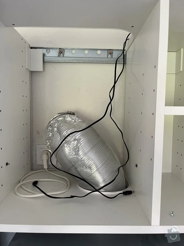 Vývod digestoře s flexibilním potrubím a elektrickým zapojením v kuchyňském skříni.